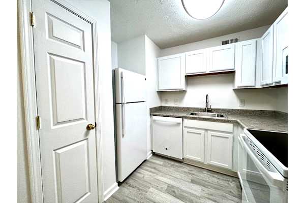 A kitchen with white cabinets and a black countertop.